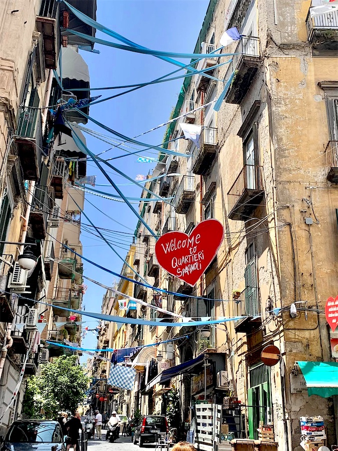 rue étroite, avec bandes de tissus bleu reliant les maisons des deux côtés de la rue, un panneau en forme de coeur souhaitant la bienvenue au quartier espagnol - Naples, Italie